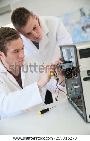Young adults fixing computer hardware in technology school