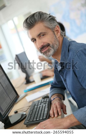 Smiling teacher working on desktop computer