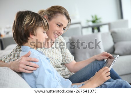 Mother and son playing with digital tablet at home