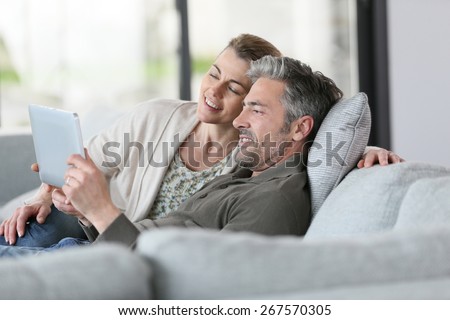 Mature couple using digital tablet relaxing in sofa