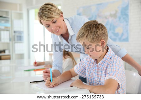 Teacher helping pupil with writing in class