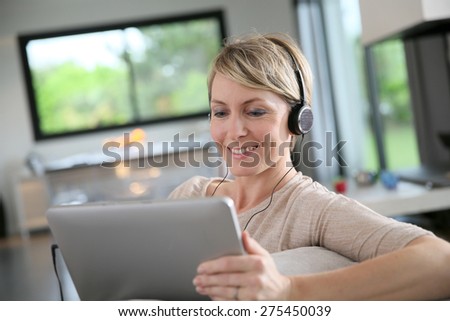 Middle-aged woman connected on tablet and wearing headset