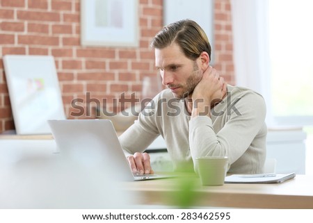 Blond guy sitting in front of laptop computer at home