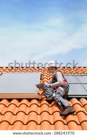 Man on roof top checking on solar panel installation