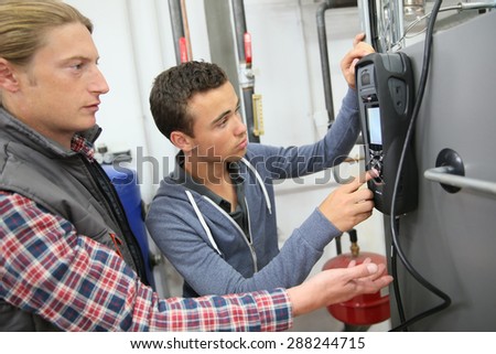 Young man in professional training measuring heat pump temperature