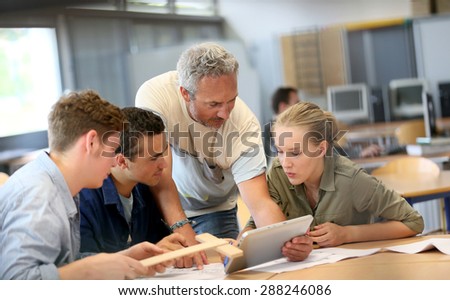 Teacher with group of students working on digital tablet