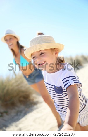Little girl pulling parents\' arms to run to the beach