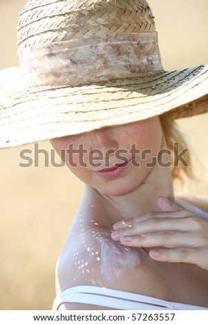 Closeup of beautiful woman spreading sunscreen on her shoulder