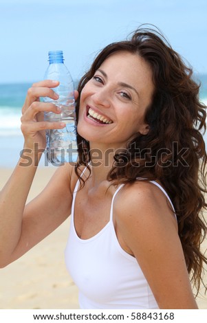 Beautiful woman drinking water at the beach