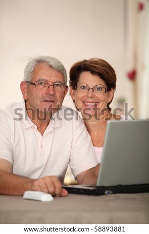 Senior couple at home with laptop computer