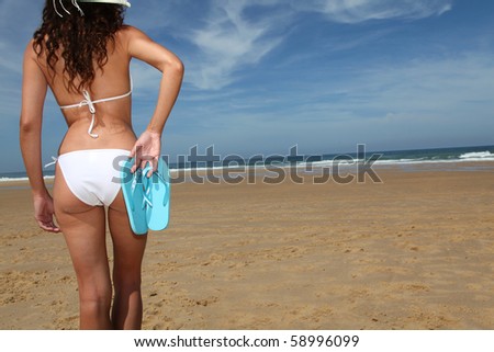 woman holding flip-flops at the beach