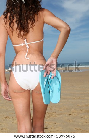 woman holding flip-flops at the beach