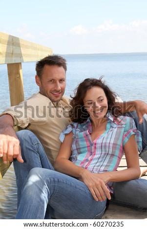 Closeup of loving couple sitting on a pontoon by a lake
