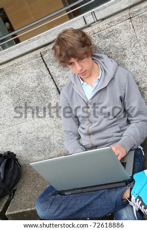 Student with laptop computer outside school building