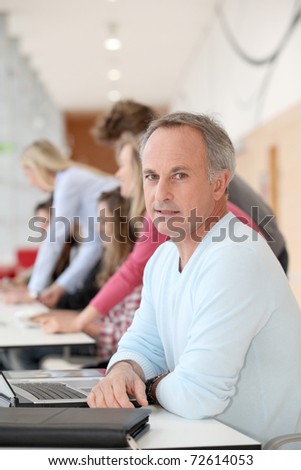 teacher working on laptop computer in classroom