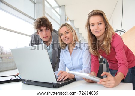 Teacher and students working on laptop computer at school