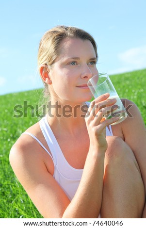 Beautiful blond woman drinking milk in countryside
