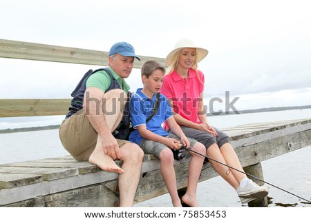 Family sitting on a pontoon with kid fishing