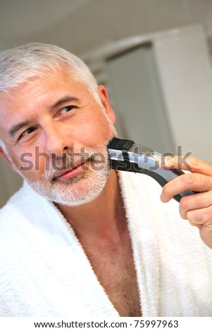 Senior man in bathroom with electric razor