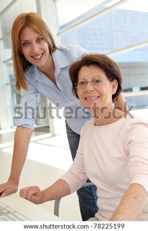 Senior woman with trainer in front of computer