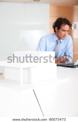 Architect in office with model of house in foreground