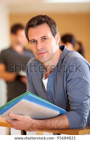 Portrait of man standing in building hall with files