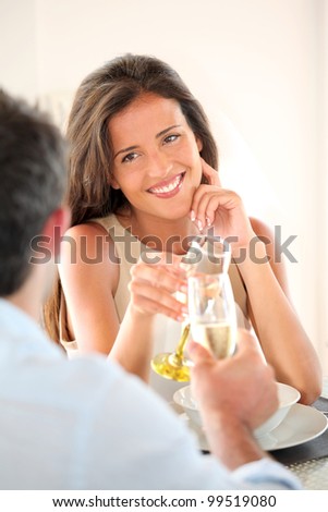 Woman cheering with glass of champaign in fancy restaurant