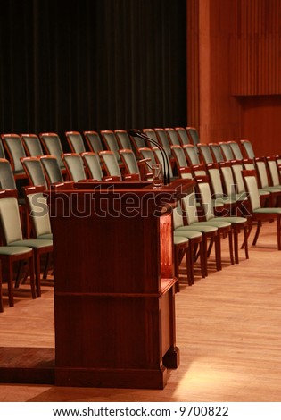 Rostrum with microphones and glass of water in empty auditorium. Prepared to business meeting