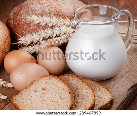 Rural still life. Bread, milk and eggs on the board.