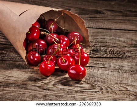 Ripe cherries in paper bags on old boards.