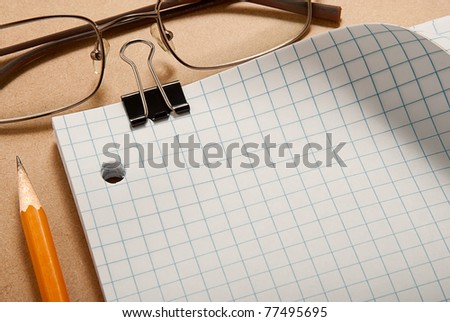 Grid paper with binder, glasses, and pencil over clip board background