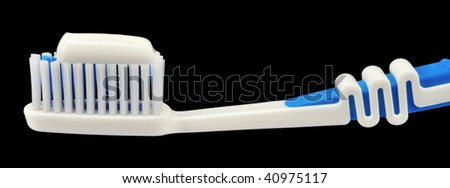 The head of a toothbrush and white tooth paste, isolated on black.