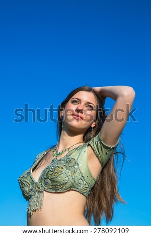 young belly dancer in front of blue sky
