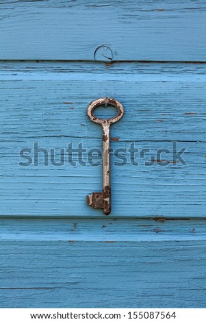 Old antique key hanging on wooden rustic blue background