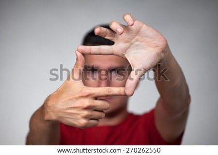 Young handsome man makes frame with his fingers