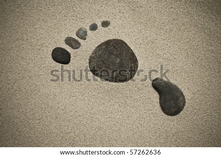 Rocks making a foot print in sand.