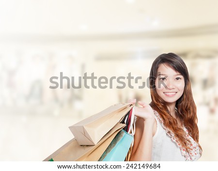 Asian businesswoman with long hair hold shopping bag sale has shopping mall background.Mixed Asian / Caucasian businesswoman.