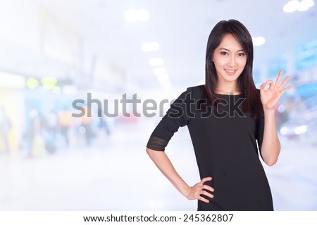portrait of asian businesswomen 20  - 30 year old showing ok sign has airport background .Mixed Asian / Caucasian businesswoman.