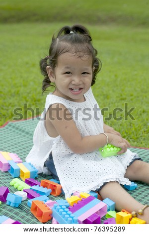 Girl smiling happily on the lawn between the play toys
