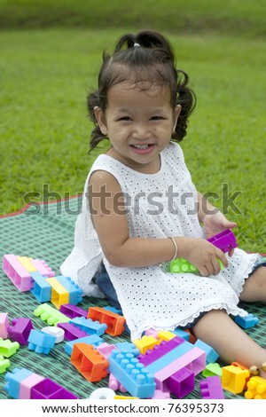Girl smiling happily on the grass between the play toys