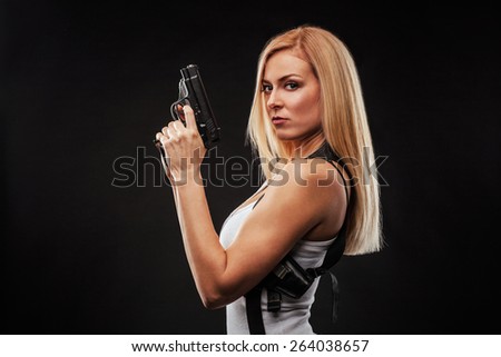Beautiful woman with gun against black background