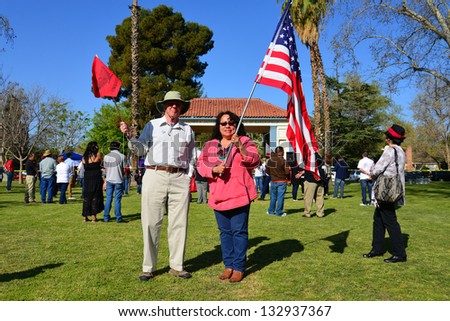 BAKERSFIELD, CA - MAR 24: A couple waves the American flag and a United Farm Workers pennant at a rally for a new immigration law on Cesar Chavez Day on March 24, 2013,  in Bakersfield, California.