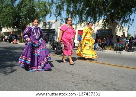 SHAFTER, CA - MAY 4: Two unidentified girls with their escort model traditional dresses as they march in the Cinco de Mayo Festival parade on May 4, 2013, at Shafter, California.
