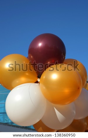 Colorful party balloons are strung together floating into a clear blue sky