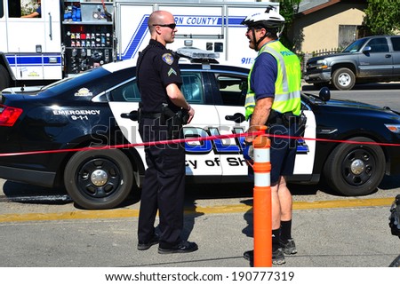 SHAFTER, CA - MAY 3, 2014: Members of the police department arrive in cars or on bikes to put up crowd control barriers before the Cinco de Mayo Celebration parade.