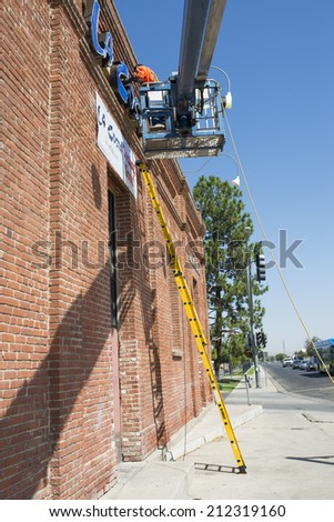 BAKERSFIELD, CA-AUGUST 21, 2014: Ted Becas works from a man lift to install an illuminated sign. An existing building is being remodeled to house a new restaurant.