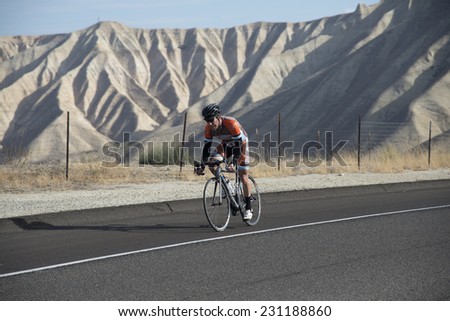 BAKERSFIELD, CA - NOVEMBER 16, 2014: An unidentified male contestant has completed a run and now speeds over the course during  the cycling portion of the Kern River Duathlon.