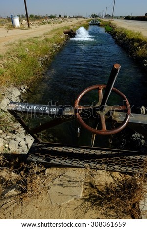 KERN COUNTY, CA - AUG 20, 2015: A sluice gate controls water levels and flows as precious ground water is pumped into an irrigation canal during drought conditions.