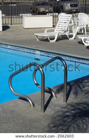 White chairs arranged around a blue swimming pool