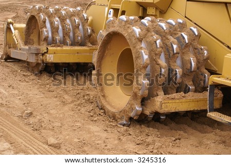 Heavy earth moving equipment prepares construction site for building — closeup of sheepshead roller